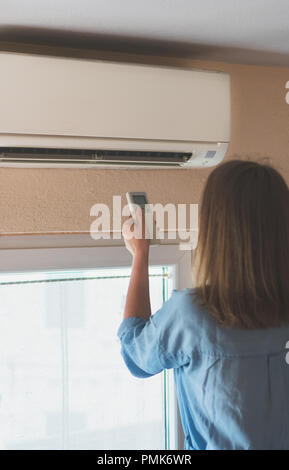 Frau mit Fernbedienung für die Klimaanlage. Stockfoto