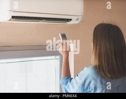 Frau mit Fernbedienung für die Klimaanlage. Stockfoto