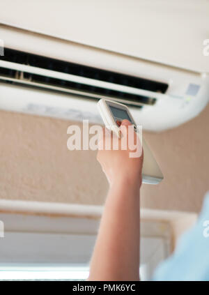 Hand, die Fernbedienung auf die Klimaanlage. Stockfoto