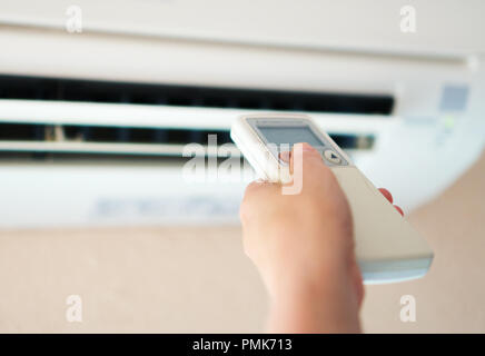 Hand, die Fernbedienung auf die Klimaanlage. Stockfoto