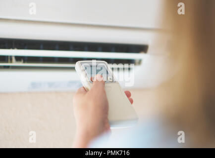 Frau mit Fernbedienung für die Klimaanlage. Stockfoto