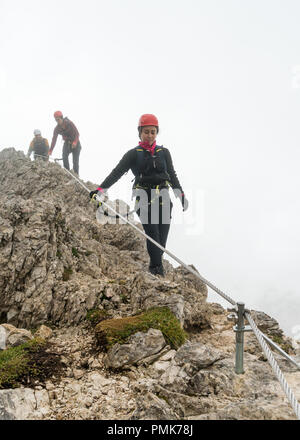 Drei junge attraktive Männliche und weibliche Bergsteiger auf einem steil und ausgesetzt Klettersteig in Alta Badia in Südtirol in den italienischen Dolomiten Stockfoto