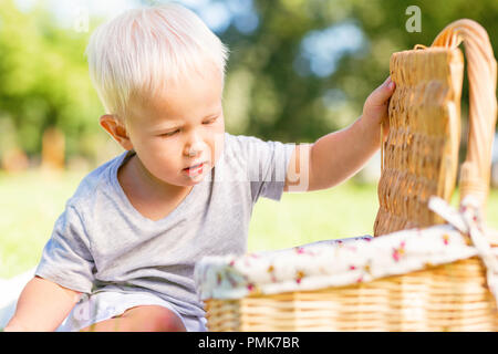 Ein wenig netter Junge Öffnung einen Korb im Park Stockfoto