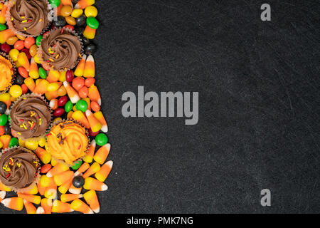 Halloween themed Süßigkeiten und Leckereien - Süßigkeiten-Mais und Muffins. Rechts ausgerichtet, schwarzer Hintergrund Stockfoto