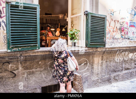 Frau im Gespräch mit Geigenbauer durch offene Werkstatt Fenster, Neapel, Italien, Europa Stockfoto