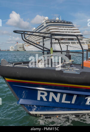 Ein rnli lifeboat mit der Navigator of the Seas massive Kreuzfahrtschiff im Hintergrund. Stockfoto