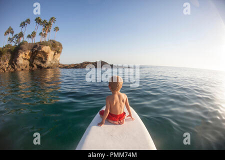 Junge sitzt auf einem paddleboard, Orange County, Kalifornien, USA Stockfoto