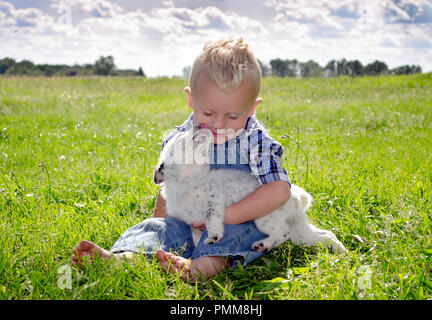 Little Boy und süßen Welpen Küsse Stockfoto