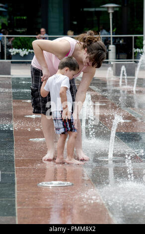 Mutter und Sohn glücklich spielen in einem städtischen splash Pad Stockfoto