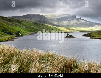 Dappled Sonne auf der Storr Berggipfel mit dem alten Mann von Storr in Wolken und Insel auf Loch Fada Isle of Skye Schottische Highlands Schottland Stockfoto