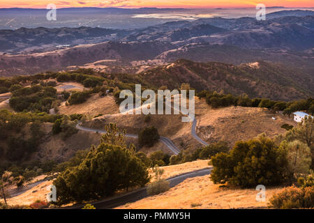 Sonnenuntergang Licht ausleuchten der Berge in South San Francisco Bay Area, kurvenreiche Straße absteigend durch Rolling Hills, San Jose, Kalifornien Stockfoto