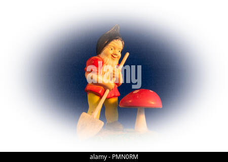 In der Nähe des Miniatur vintage Gartenarbeit gnome mit einer kleinen Schaufel und rote Gift Fliegenpilz, Pilz auf Vignette Hintergrund Stockfoto