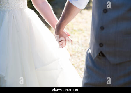 Neu verheiratete Paare halten sich an den Händen an eine australische Land Hochzeit Stockfoto