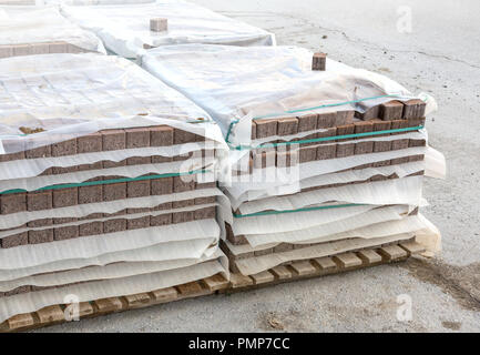 Beton oder Kopfsteinpflaster graues Quadrat Gehwegplatten oder Steine für Boden, Wand oder Pfad auf Holzpalette in Werks- und Lagergebäude gestapelt. Industrie Fertigung Stockfoto