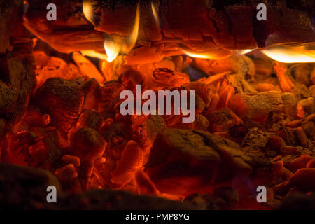 Closeup glühende Kohle und Brennholz im Kamin Hintergrund Stockfoto