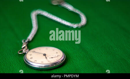 Taschenuhr mit Kette auf grünem Hintergrund Stockfoto