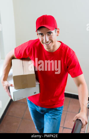Lieferung Mann in der roten Uniform holding Kartons Stockfoto
