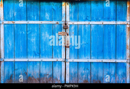 Die alte große Holztüren in blau lackiert und geschlossen auf das Vorhängeschloss. Das blaue Tor auf das Schloss. Holz- toren closeup, für Hintergrund Stockfoto