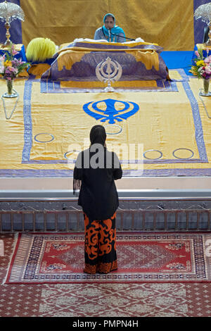 Eine anonyme Frau worshipper im Gebet vor dem Altar und Frau preist an Baba Makhan Shah Lobana Tempel in Queens, New York. Stockfoto