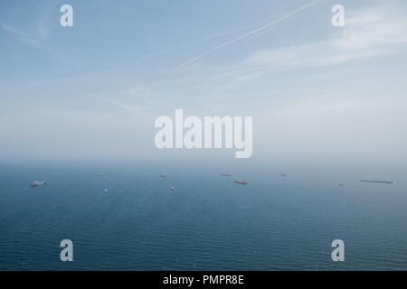 Ein Blick nach unten auf einer belebten Versand Kanal mit Frachtschiffe und Tanker auf dem Weg zum Meer. Das blaue Meer Mischungen in den Himmel. Mittelmeer Stockfoto