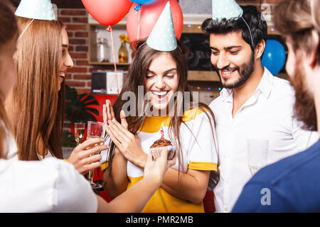 Freunde gratuliert brunette Geburtstag Mädchen in der Partei hat mit Kuchen, sie Gefühl überrascht Stockfoto