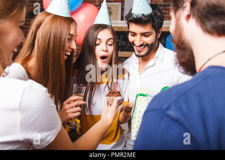 Aufgeregt brunette Geburtstag Mädchen bereit, Kerze zum Geburtstag Kuchen am Geburtstag Party in der Küche zu blasen Stockfoto