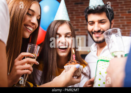 Awesome brunette Geburtstag Mädchen in einer Partei hat Lachen und immer bereit, die Kerzen auf dem Kuchen auszublasen Stockfoto