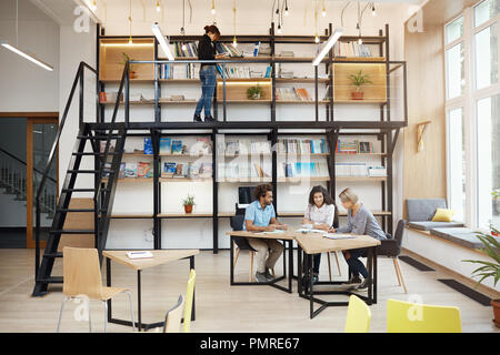 Drei glückliche begeistert Designer diskutieren buisness Ideen für das bevorstehende Projekt am Tisch sitzen mit Papieren in hellen, modernen Bibliothek. Komfort Teamarbeit mit Freunden. Anlauf, Geschäftskonzept. Stockfoto