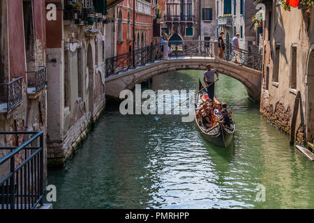 Gondel Touristen, die in einem engen Kanal in Venedig, Italien. Stockfoto