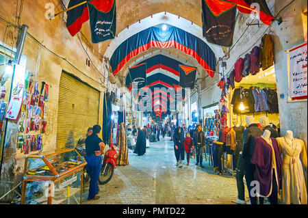 KASHAN, IRAN - Oktober 22, 2017: mittelalterliche Gebäude des Grand Basar mit schmale Gasse, voller Geschäfte, Marktstände, Besucher und dekoriert mit Muharram Stockfoto