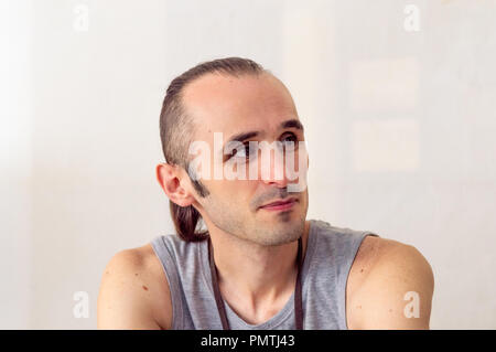 Brunet Mann mit stilvollen Haar denken und suchen seitwärts auf weißem Hintergrund Stockfoto