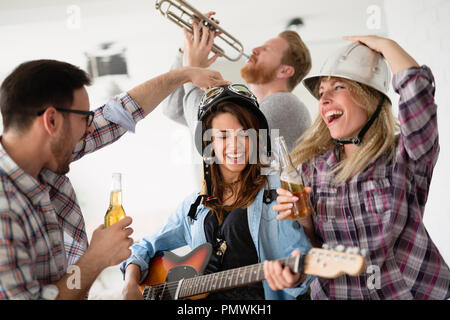 Glückliche Gruppe befreundeter Instrumente spielen und feiern Stockfoto