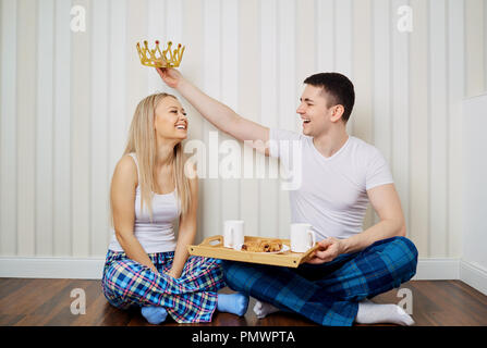 Ein glückliches Paar in den Schlafanzügen sitzen auf dem Boden eine gestreifte Wand backgr Stockfoto