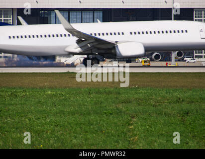 Ein Flugzeug nähert sich mit Hangar in den Hintergrund und die Wiese im Vordergrund. Stockfoto