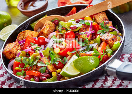 Hausgemachten warmen schwarzen Bohnen und Mais salsa Salat mit Tomaten und Paprika, gebratenem Tofu Käse, Limonensaft und Olivenöl Dressing in einer gusseisernen Pfanne o Stockfoto