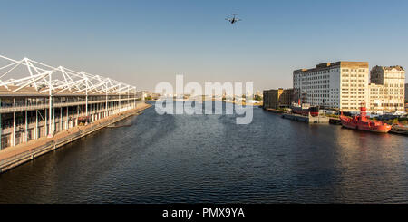 London, England, Großbritannien - 2 September, 2018: Eine kleine Passagier Flugzeug fliegen tief über Royal Victoria Dock, durch das Ausstellungszentrum ExCeL flankiert und Mühle Stockfoto