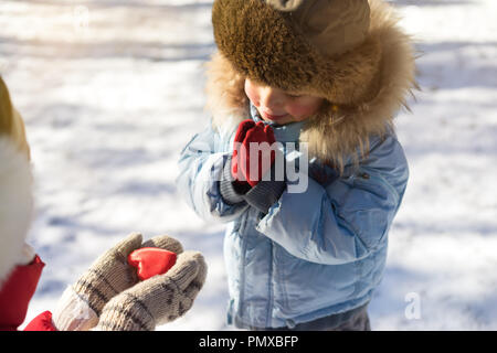 Frau mit roten Herzen outdoor im fäustlinge und zeigen, kleine Jungen Stockfoto