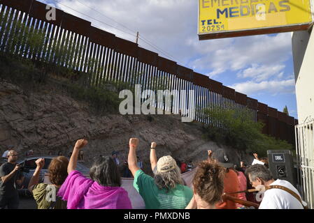 Demonstranten in Nogales, Sonora, Mexiko, heben ihre Fäuste in die Grenzmauer in Nogales, Arizona, USA, während eines Protestes der Erschießung eines jugendlich in Mir Stockfoto