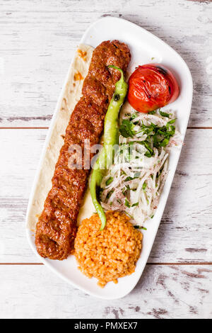 Adana Kebab mit grünem Gemüse in weißer Teller serviert. Stockfoto