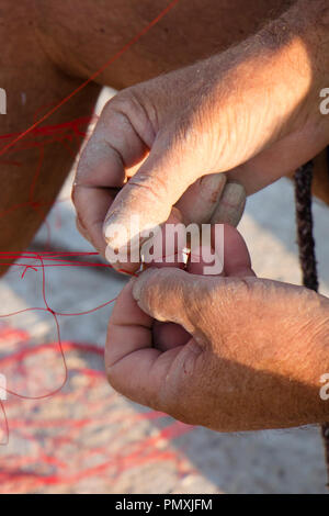 Fischer Hände Instandsetzung sein rot Fischernetz, Nahaufnahme, Detail Stockfoto