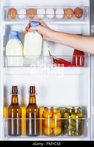 Zugeschnittenes Bild des Menschen, die Flasche Milch aus dem Kühlschrank Stockfoto