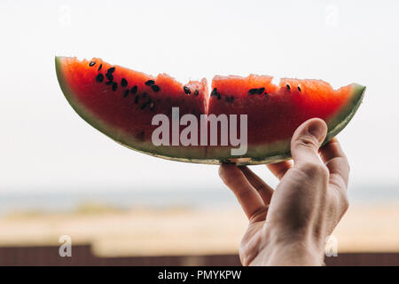 Ein Stück reifer Wassermelone in die Hand eines Mannes, in der Nähe Stockfoto