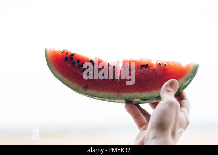 Ein Stück reifer Wassermelone in die Hand eines Mannes, in der Nähe Stockfoto