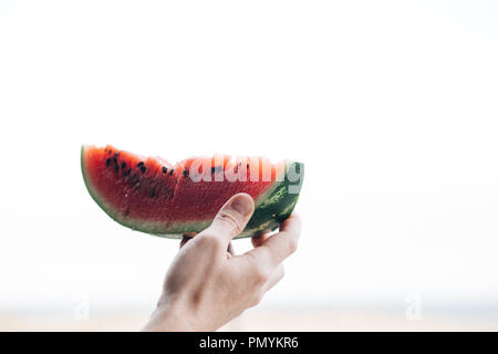 Ein Stück reifer Wassermelone in die Hand eines Mannes, in der Nähe Stockfoto