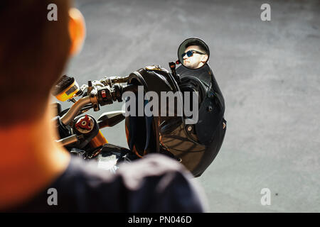 Nahaufnahme von Stattlichen biker sitzen auf dem Motorrad und reflektieren im Rückspiegel. Stockfoto
