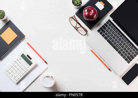 Blick von oben auf die Arbeitsplatz mit Rechner, Schreibwaren, Kaffee und digitale Geräte auf Tisch Stockfoto