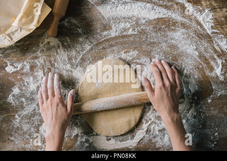 7/8 Schuß von Frau Teig vorbereiten mit Rolling Pin auf rustikalen Holztisch Stockfoto