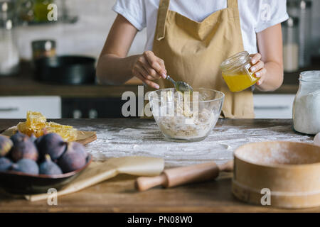 7/8 Schuß von Frau gießen Honig in die Schüssel während pie Vorbereitung Stockfoto