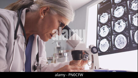 Im mittleren Alter Neurologe weibliche Untersuchung mit Mikroskop Stockfoto