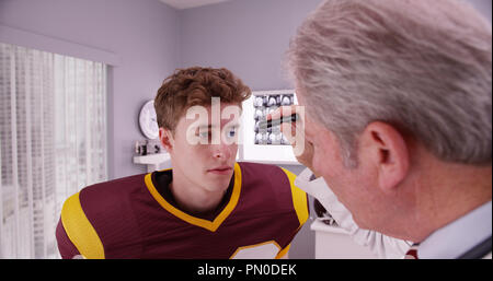 Mitte - gealterte Arzt untersuchen Fußballspieler nach gehirnerschütterung. Stockfoto